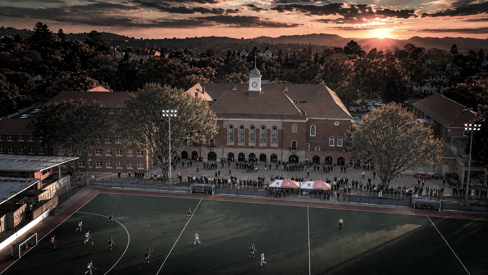 Aerial view of a hockey turf at sunset with players mid-game.